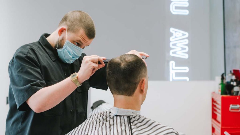 cabelereiro cortando cabelo de cliente em salão de beleza