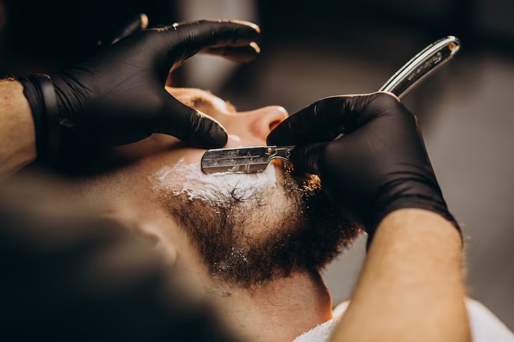 7 Ferramentas para Barbeiros que são Essenciais - barbeiro fazendo uma barba com navalha