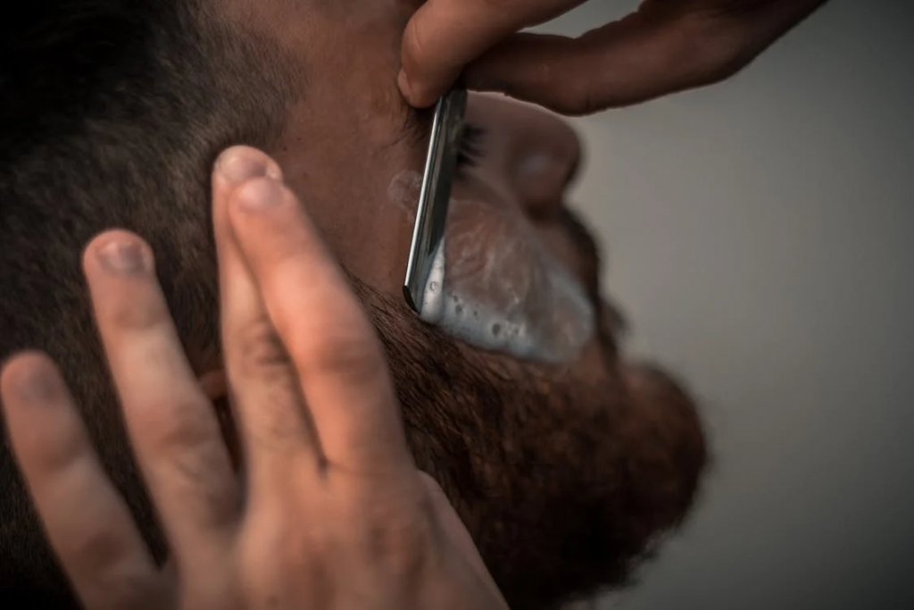 Esterilização em Barbearias: Entenda Como Garantir Segurança e Higiene aos Clientes - barbeiro fazendo uma barba